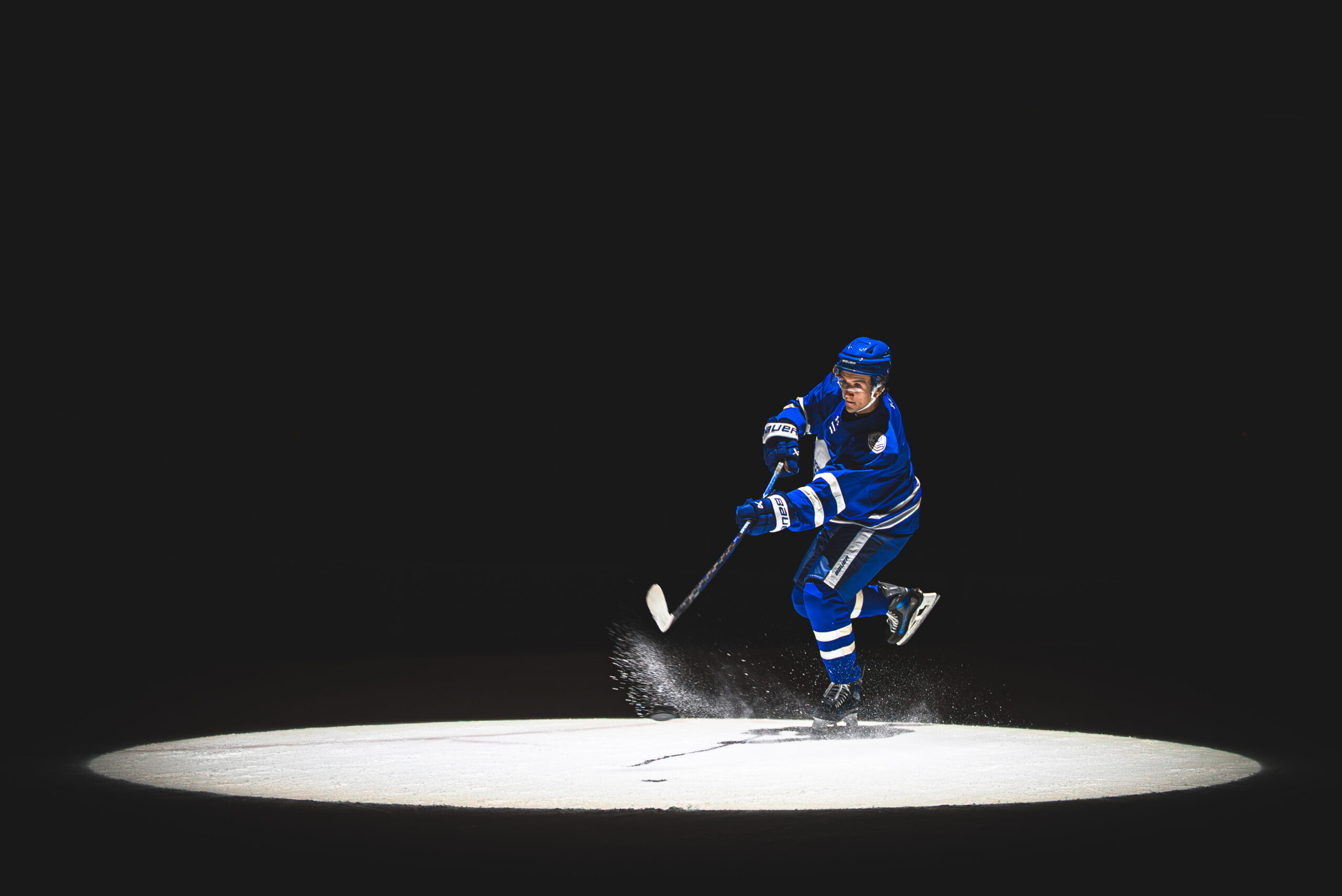 A Regiment player in a St. John's Maple Leafs jersey takes a shot under a spotlight
