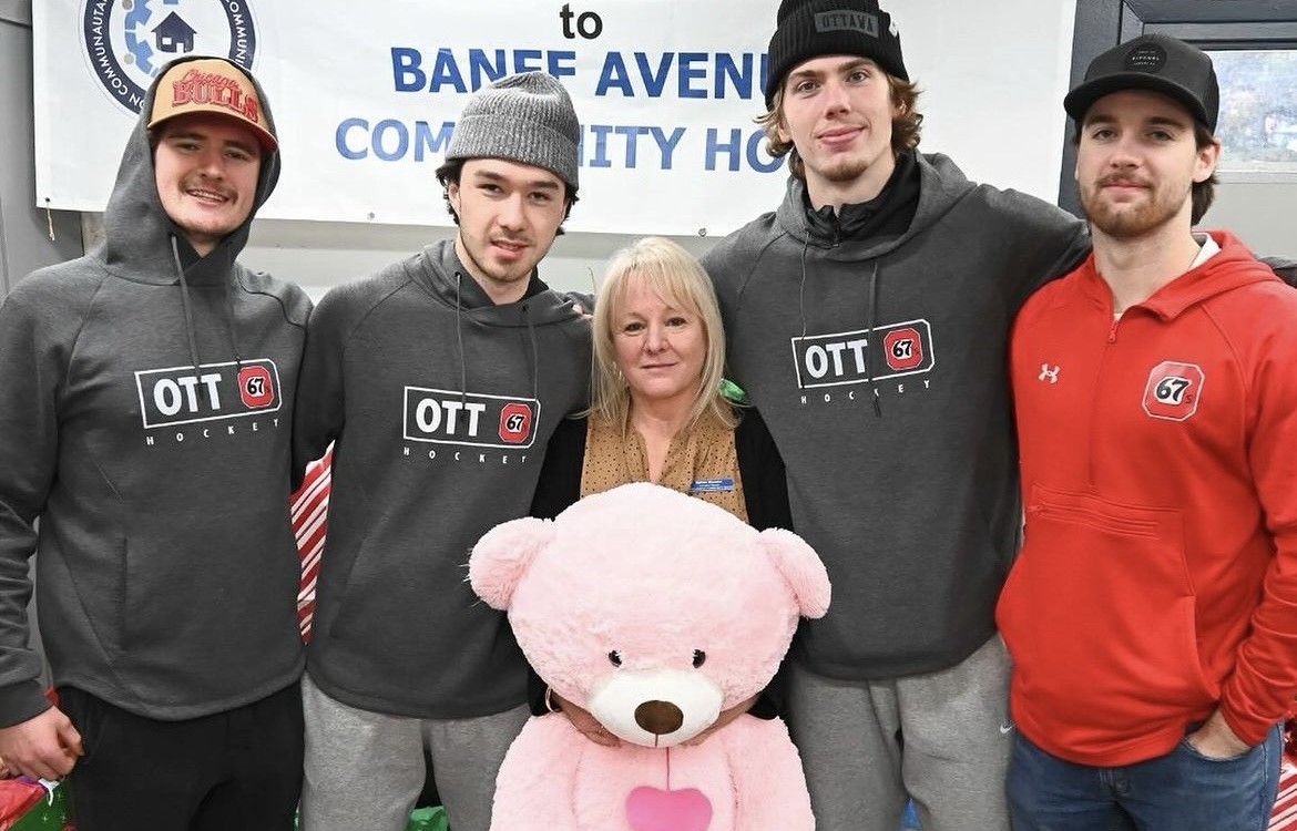 67's players delivering toys and a woman holding a pink bear